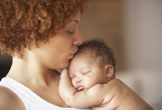 Profile of mother kissing sleeping baby on head