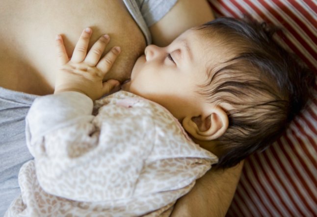 Mother breastfeeding baby girl (0-1 month)