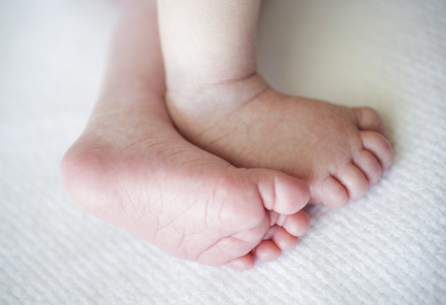 Close-up of newborn baby boy's (0-1 month) feet on white blanket