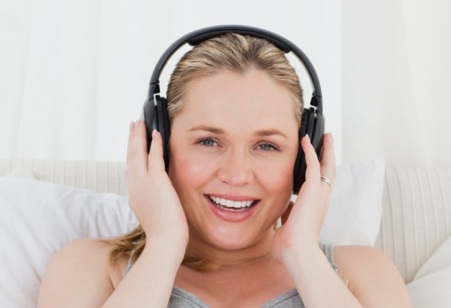 Lovely Pregnant Woman Listening To Music on her Bed