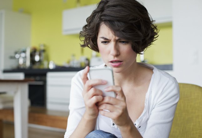Young woman in domestic kitchen text messaging